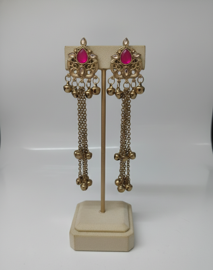 Close-up view of premium artificial Antique Gold Tone Long Tassel Ghungroo Earrings with Rani Pink Stone Accents by Innovate Art Impex.