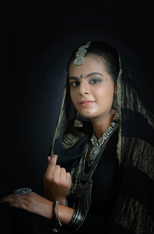 a woman wearing a veil and jewelry poses for a photo