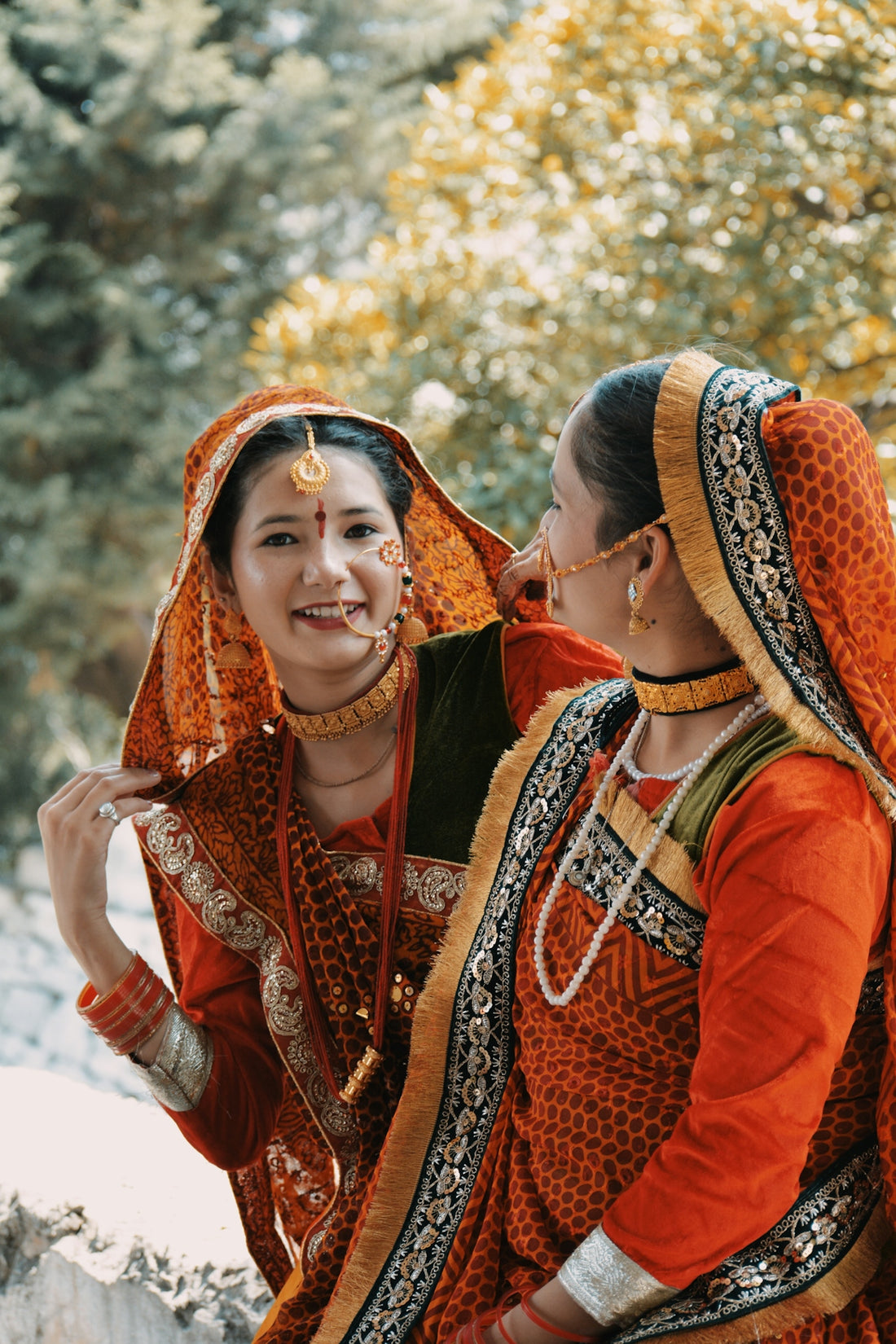 Two women are smiling in traditional clothing.