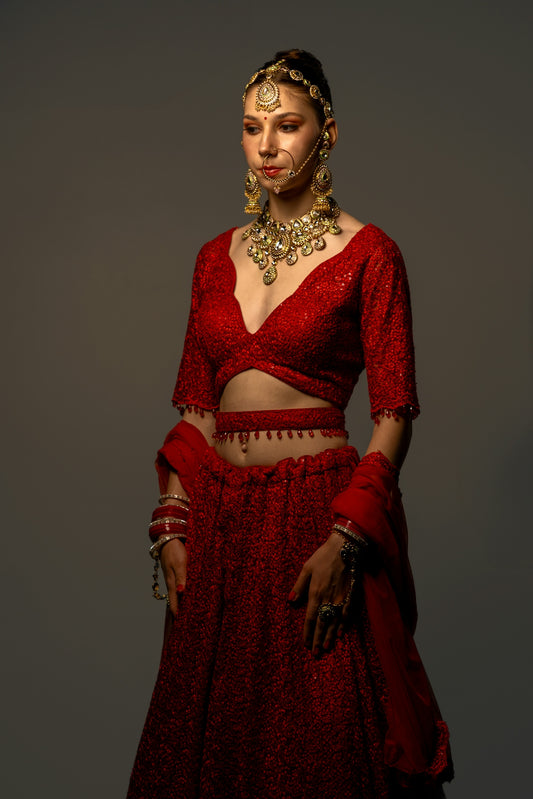 A woman models a beautiful red indian outfit.