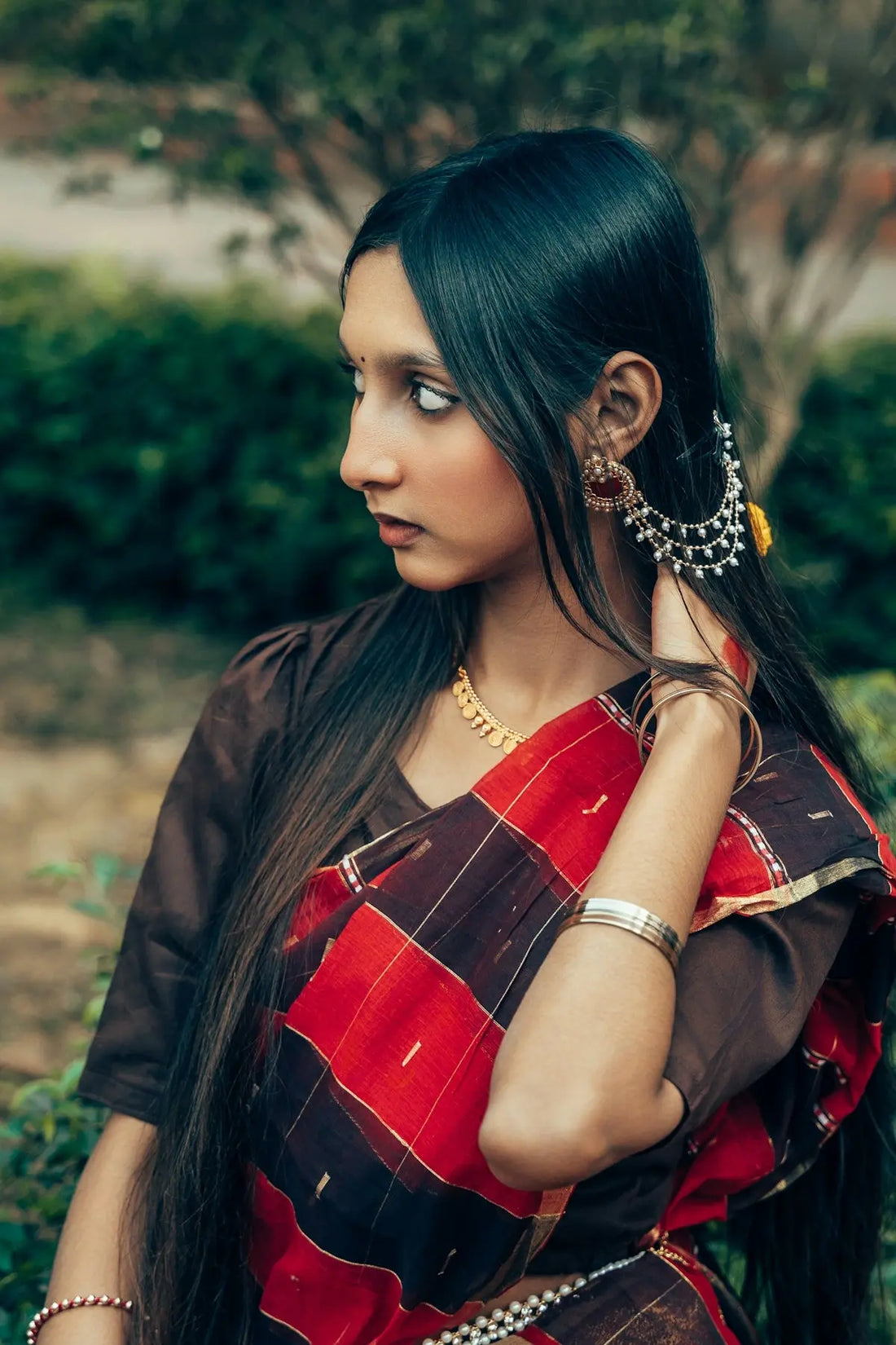 A young woman wearing a traditional indian saree and jewelry.