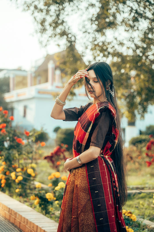 A woman in a traditional sari stands in a garden.