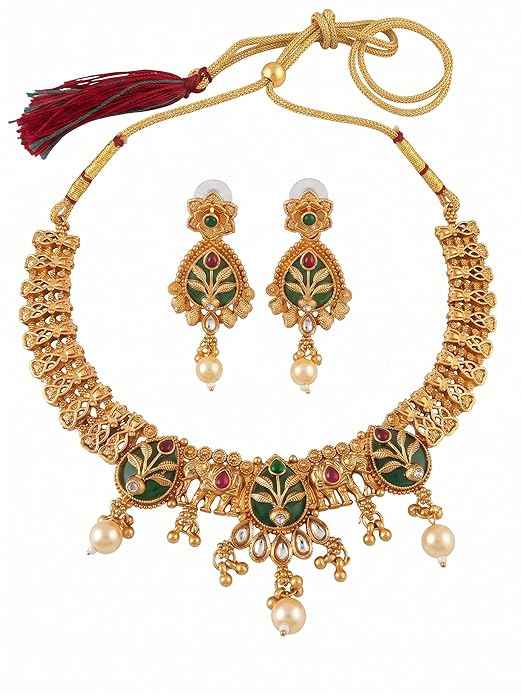 Close-up of INNOVATE ART IMPEX traditional gold Rajwadi choker necklace and matching dangle earrings featuring green floral enamel work, red stones, and pearl drops on a white background.