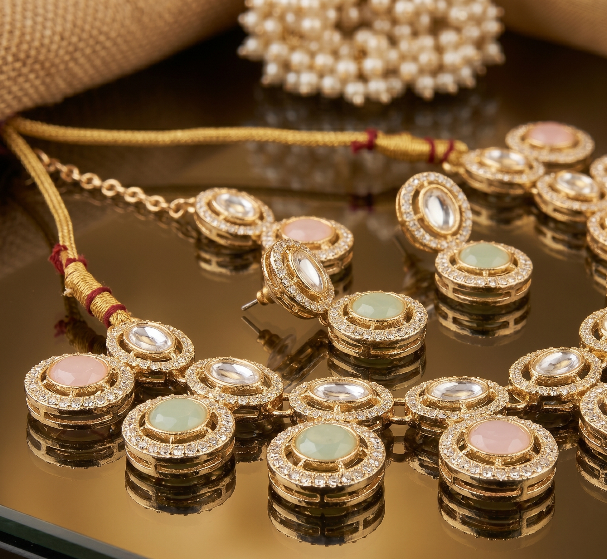 Gold jewelry set with gemstones on a reflective surface