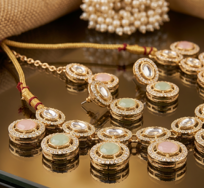 Gold jewelry set with gemstones on a reflective surface
