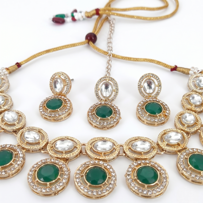 Jewelry set with necklace, earrings, and bangles featuring green stones and gold accents on a white background.