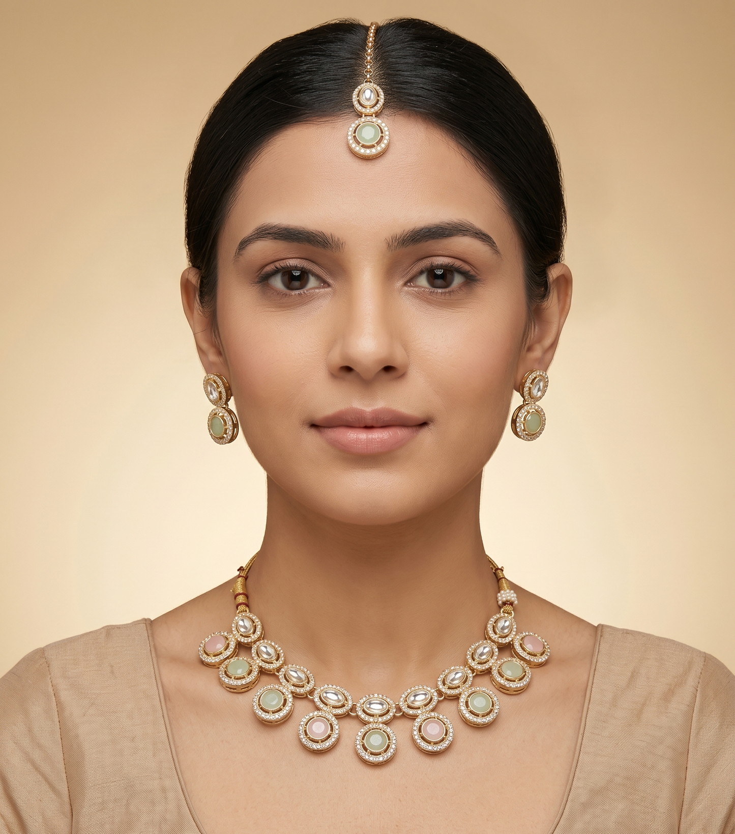 Woman wearing a gold necklace and earrings on a beige background