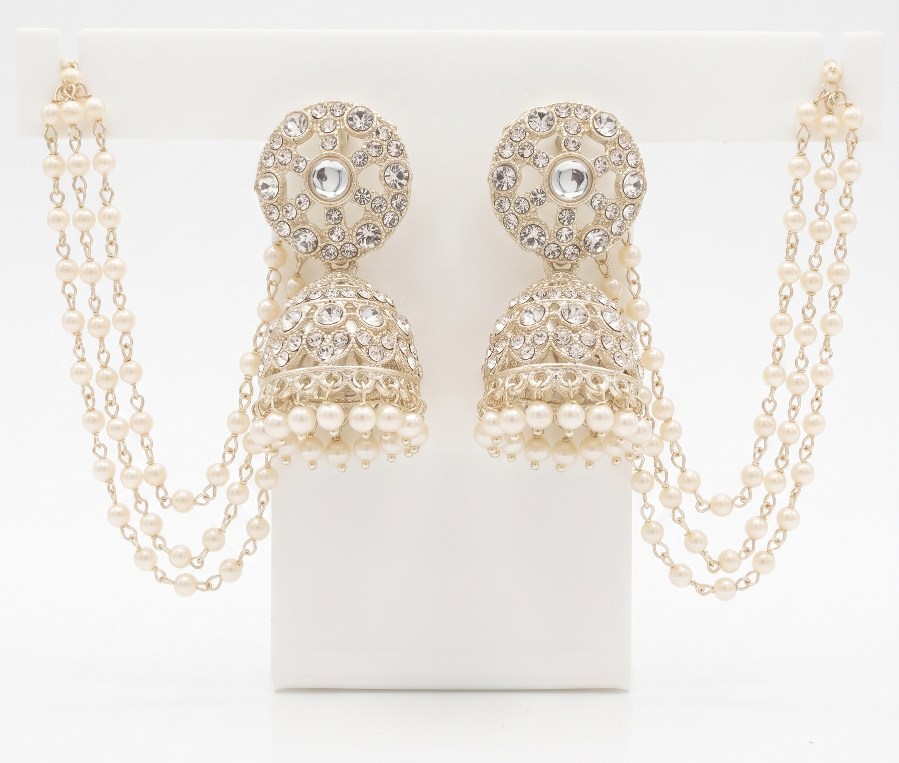 Pair of gold and pearl earrings with chains on a white background