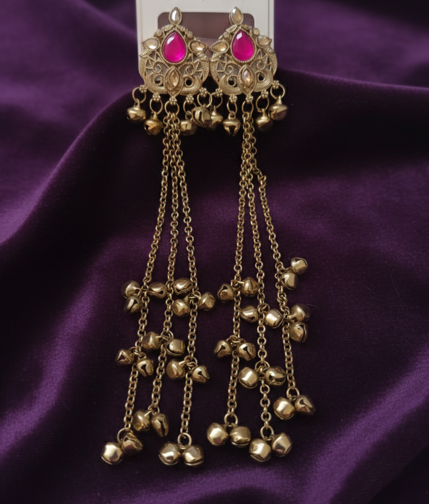 Close-up view of premium artificial Antique Gold Tone Long Tassel Ghungroo Earrings with Rani Pink Stone Accents by Innovate Art Impex.