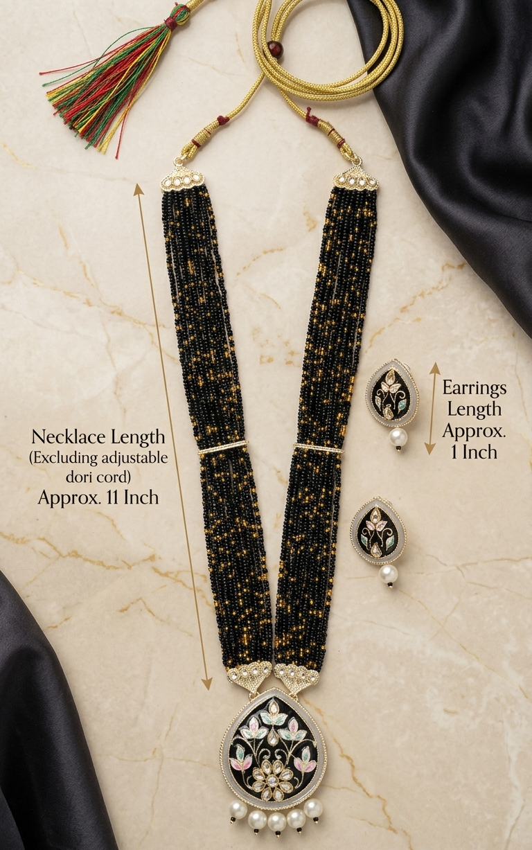 Black beaded necklace with floral pendant and matching earrings on a beige background