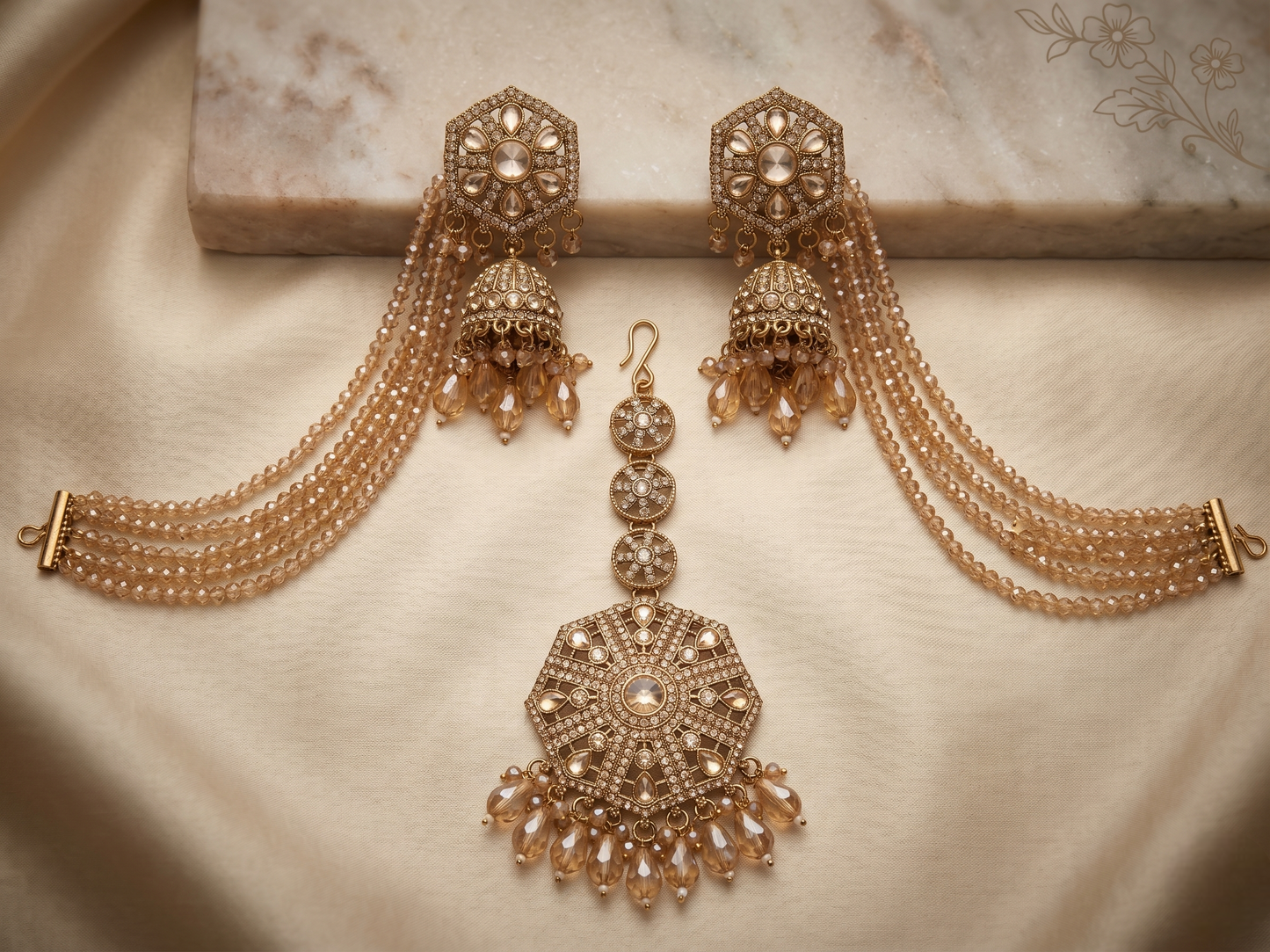 Ornate gold earrings with intricate designs on a beige fabric background