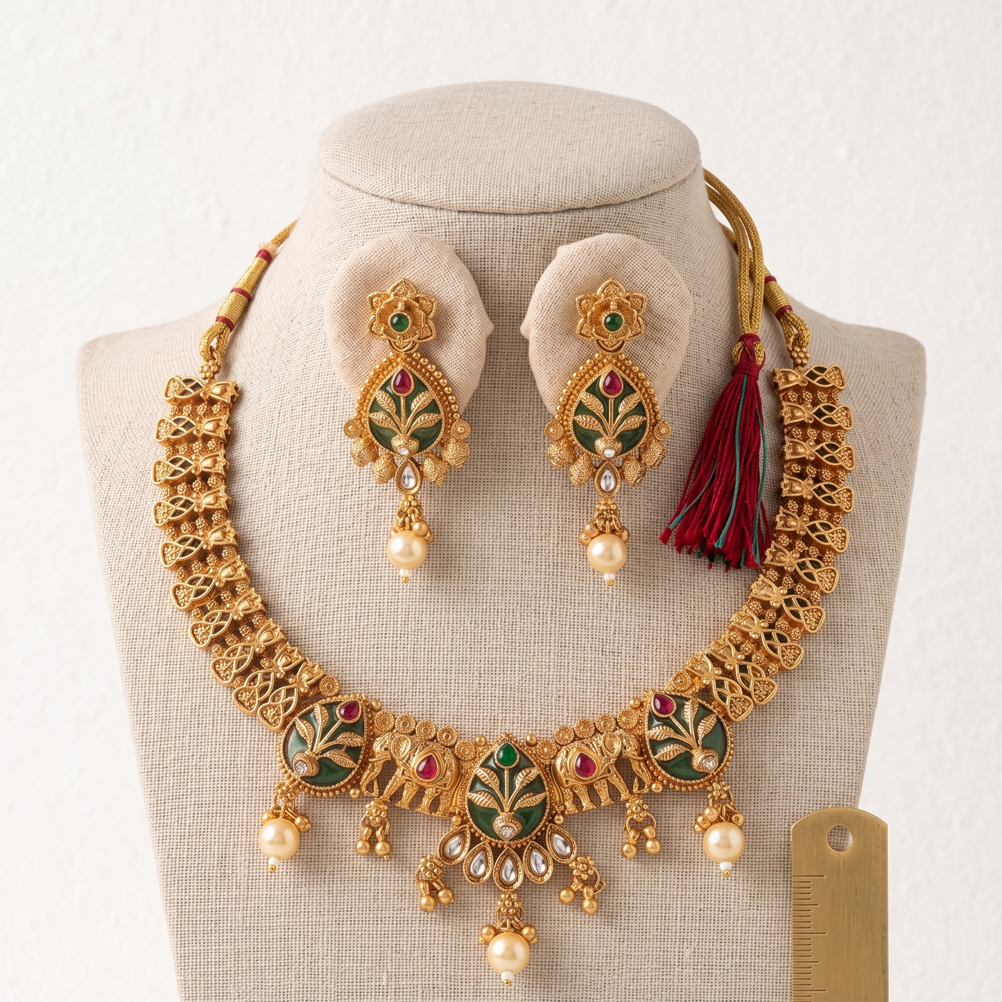 Gold necklace and earrings set on a mannequin with a white background