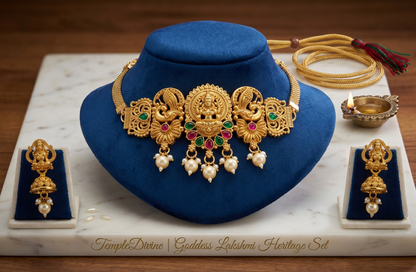 Gold necklace with pendants on a blue velvet stand, surrounded by other jewelry items on a marble surface.
