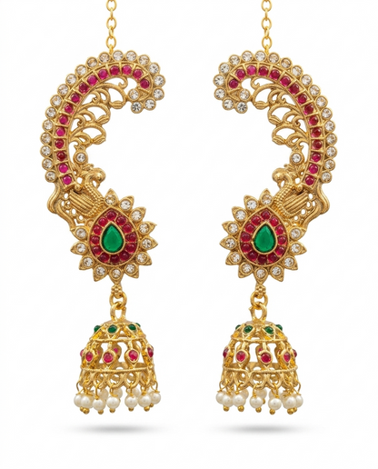 Pair of INNOVATE ART IMPEX antique gold peacock ear cuff kaan chain jhumkas with red and green stones on a clean white background.